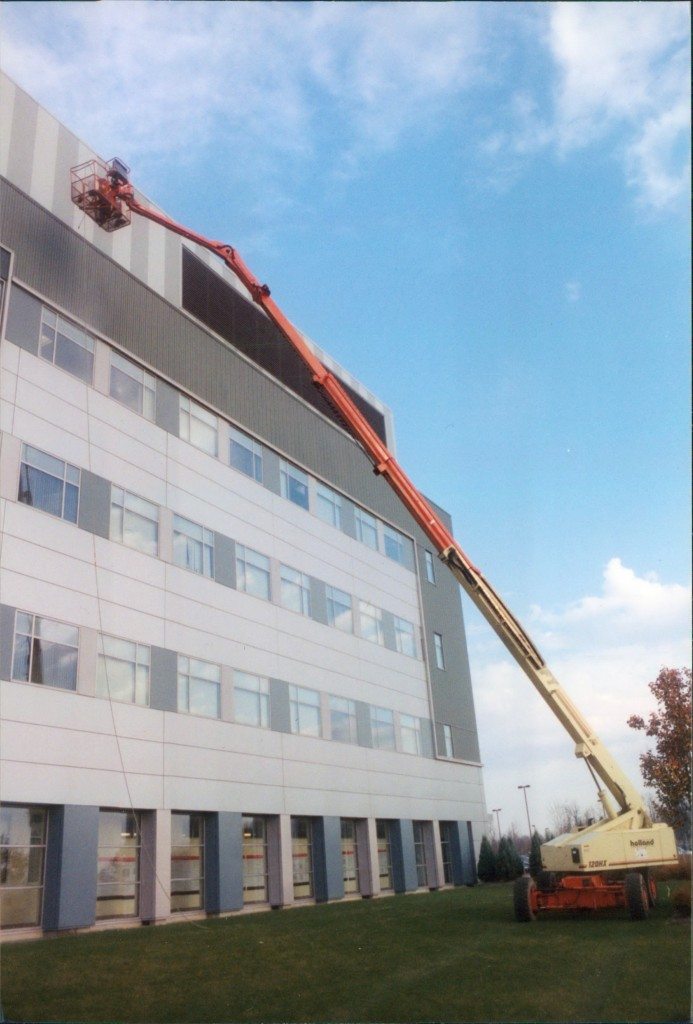 Cleaning aluminum siding on building using 120 foot man lift